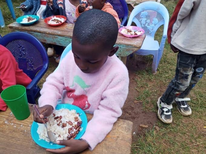 Shekina at the feeding center, eating a plate of rice and beans