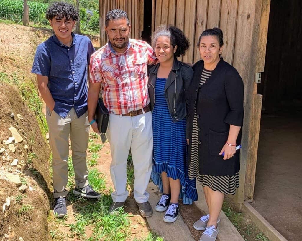 Pastor Franklin and his family standing beside their repaired truck, smiling with gratitude for the assistance received.