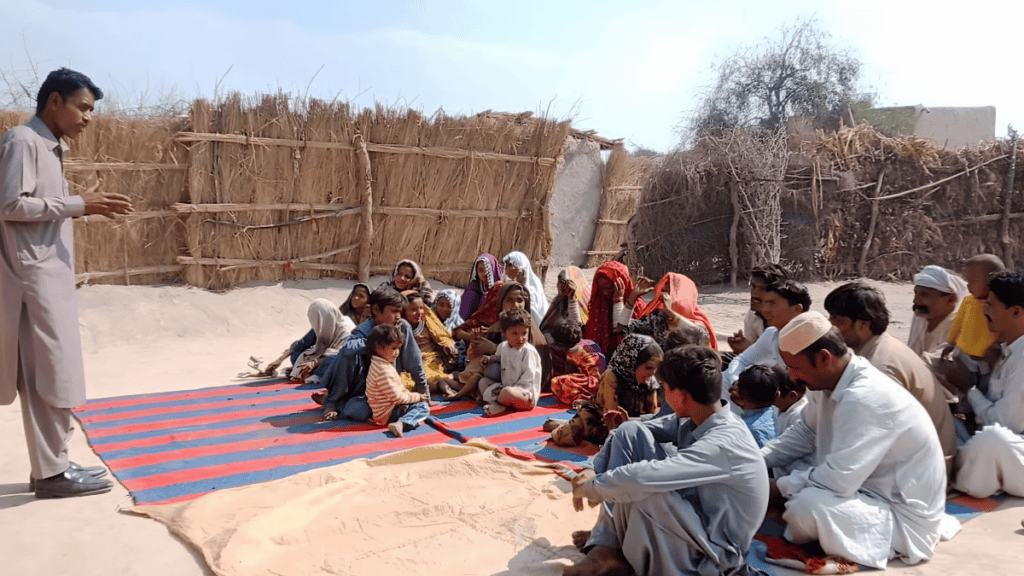 An open-air gathering of a Marwari community, attentively listening to a preacher on a colorful mat, showcasing a moment of shared learning and communal bonds.