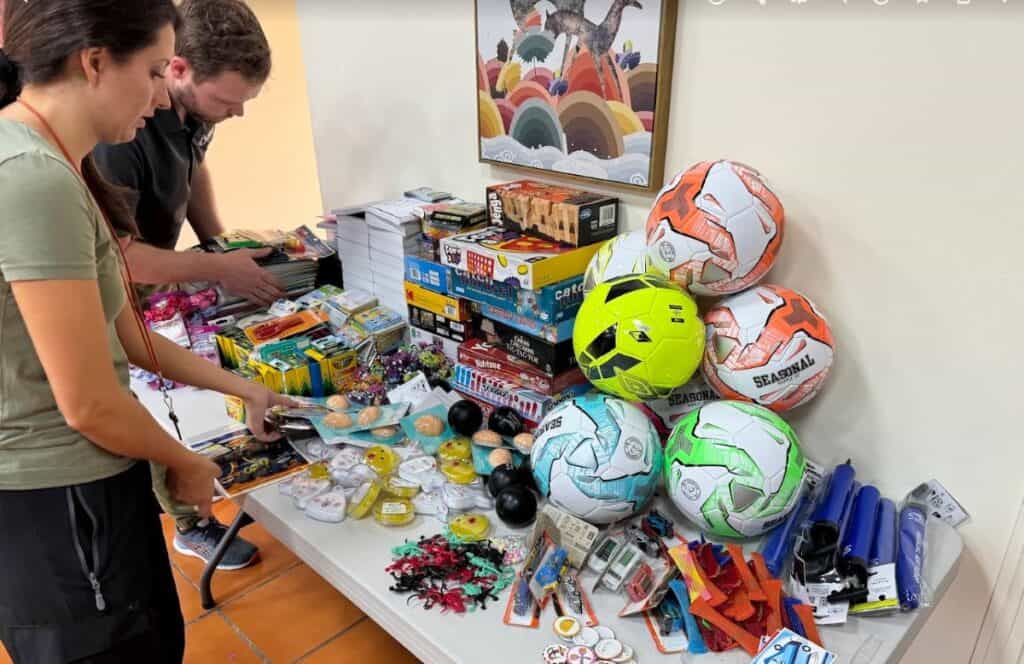 A table filled with donated items such as school supplies, toys, and sports equipment for children in Honduras.