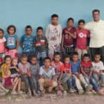 The Tolupan village of Monte Rey, seen here is their school with 18 children sitting and standing outside of the blue painted school building.