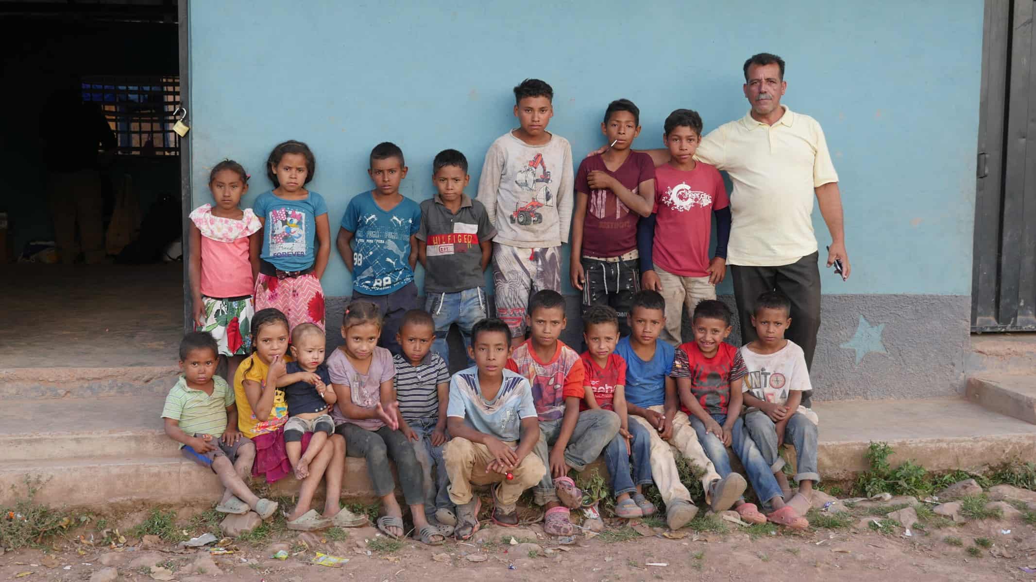 The Tolupan village of Monte Rey, seen here is their school with 18 children sitting and standing outside of the blue painted school building.