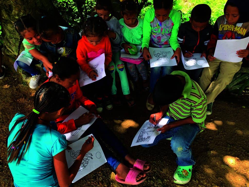 Children coloring with the supplies that they have.