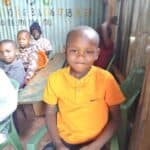 Bonface Gichuru, in an orange shirt, sits with other children at the Agape feeding center in Kenya