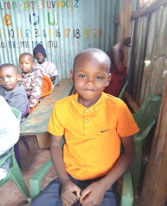 Bonface Gichuru, in an orange shirt, sits with other children at the Agape feeding center in Kenya